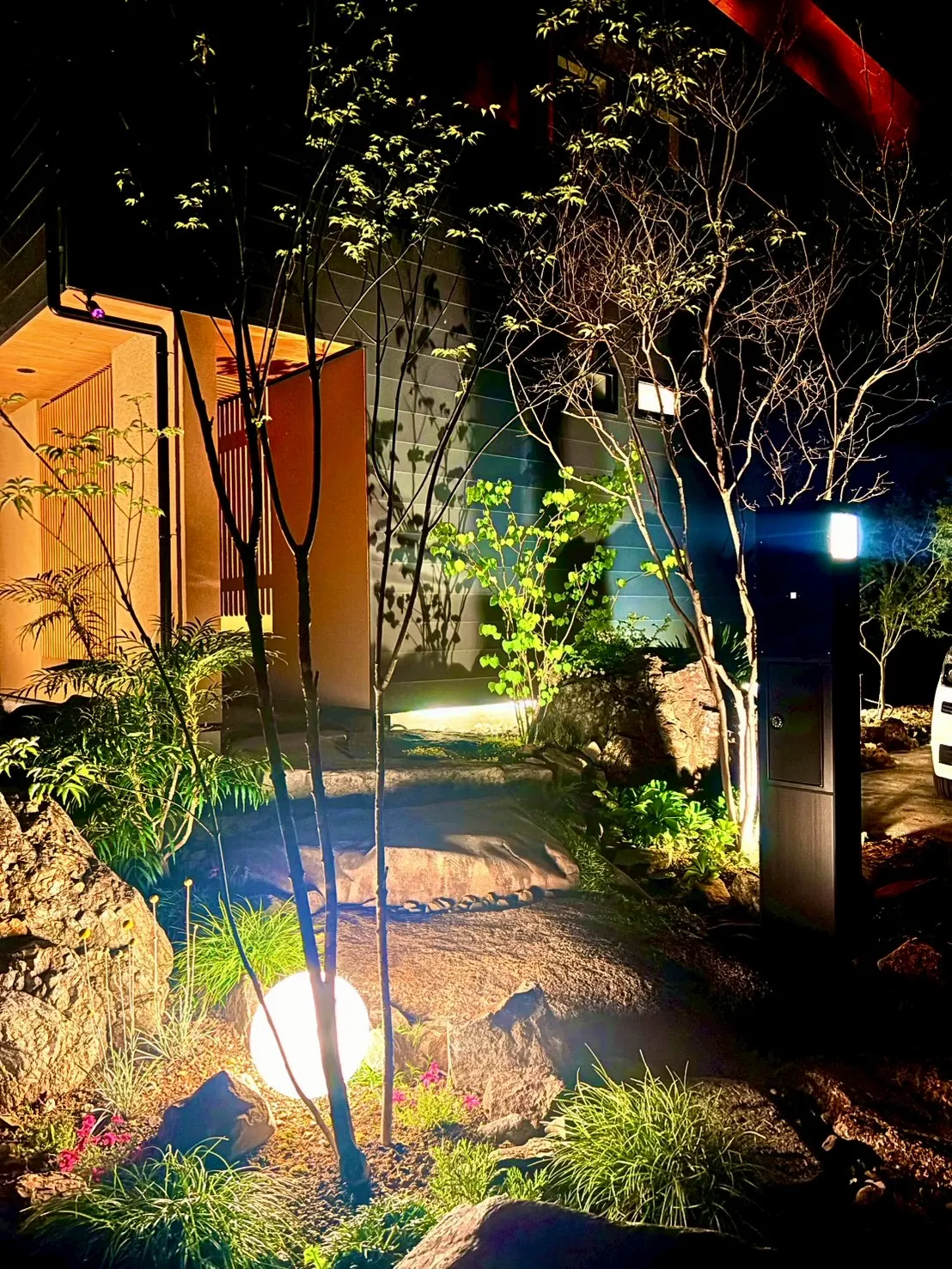 夜の庭。球体の灯りが植栽と石を照らす