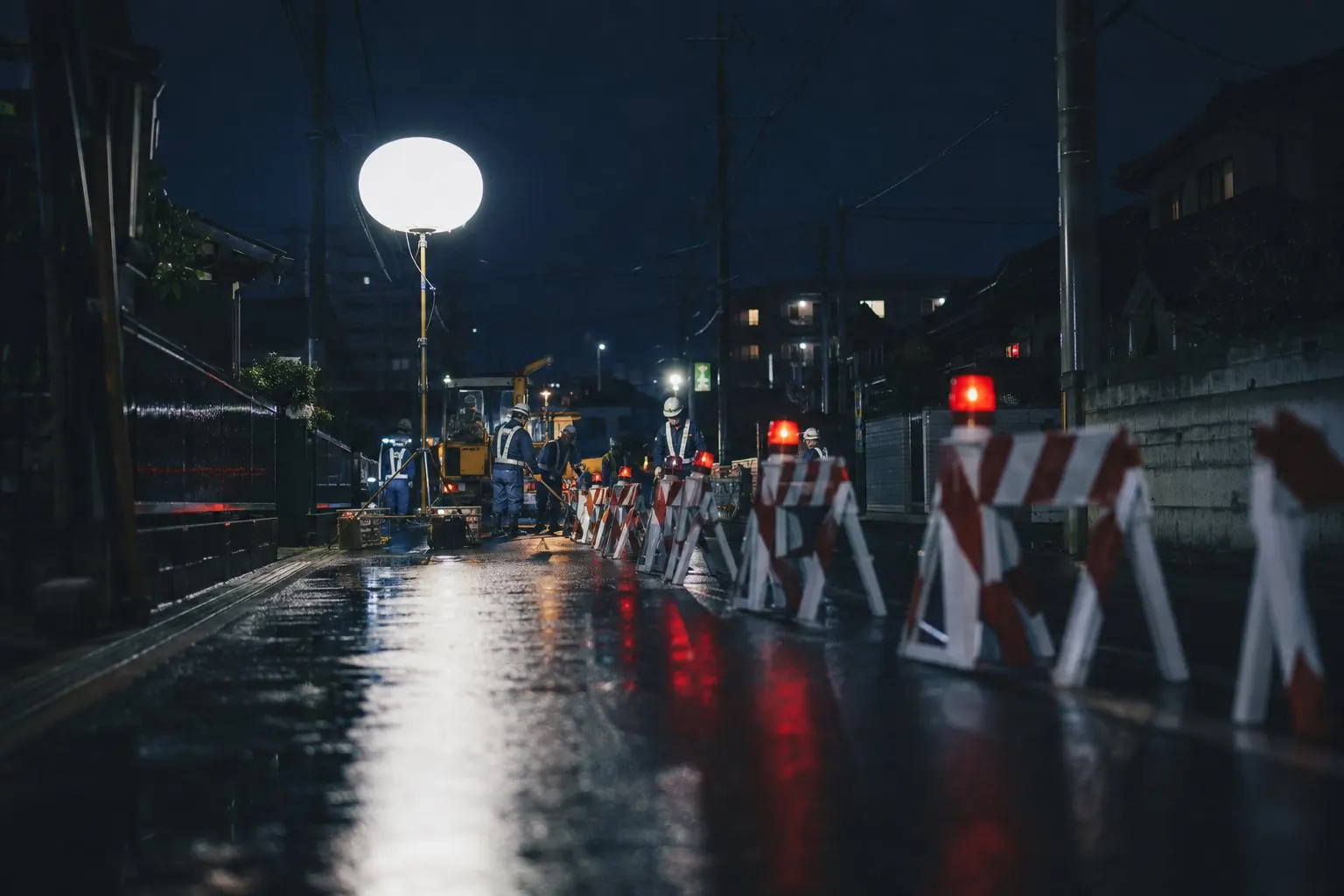 バルーン投光器と保安灯が並ぶ夜間道路工事のイメージ